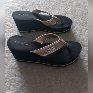 GUESS women's wedge sandals in gold with a black sole.